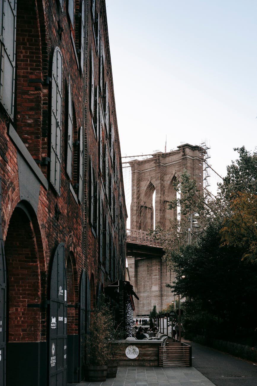 Classic view of the Brooklyn Bridge with historic urban architecture and foliage.