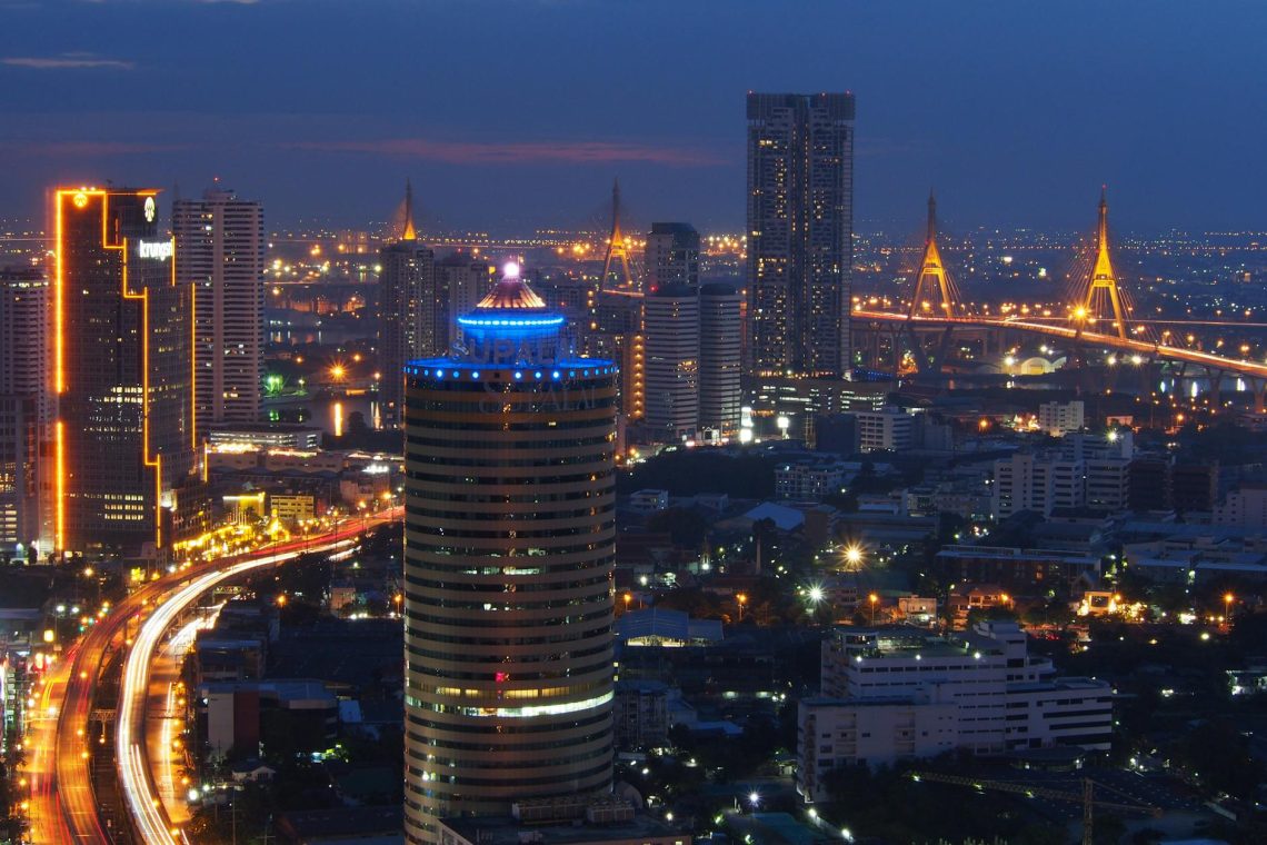 A breathtaking view of Bangkok's illuminated skyline with glowing buildings and the Chao Phraya River.