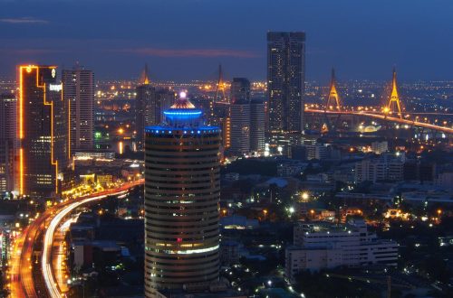 A breathtaking view of Bangkok's illuminated skyline with glowing buildings and the Chao Phraya River.