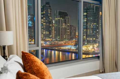 An elegant view of Dubai Marina's night skyline through a luxurious hotel window.