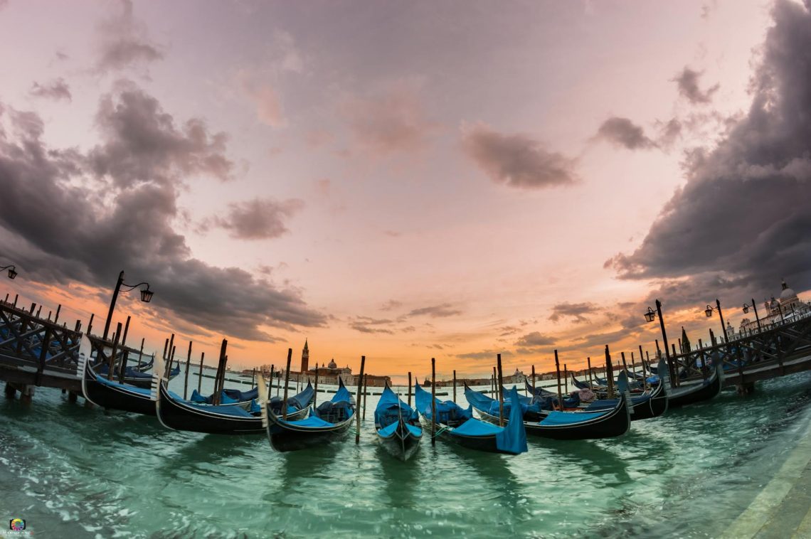 Gondolas docked at sunset in scenic Venice, capturing a serene waterfront view.