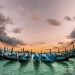 Gondolas docked at sunset in scenic Venice, capturing a serene waterfront view.