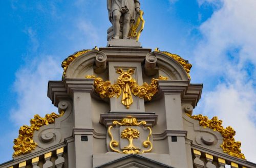 Ornate architectural detail with golden statue against a blue sky in Brussels, Belgium.