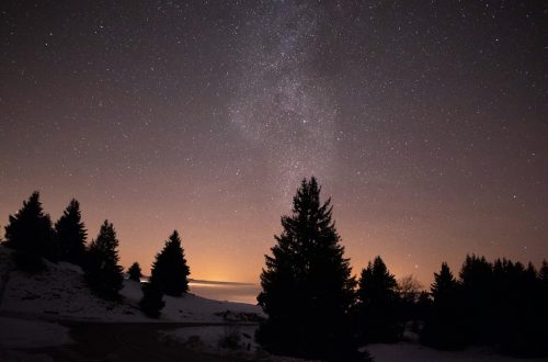 A serene starry night sky over snowy trees in Viuz-la-Chiésaz, capturing the Milky Way.