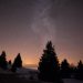 A serene starry night sky over snowy trees in Viuz-la-ChiƩsaz, capturing the Milky Way.