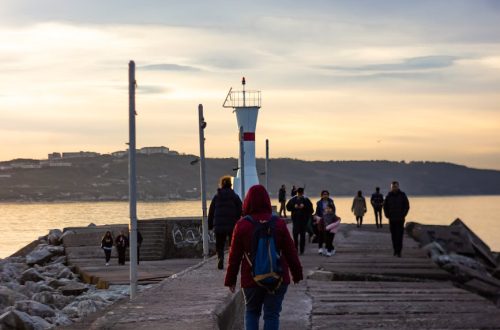 People walking on a jetty during sunset in Istanbul, creating a serene coastal landscape.