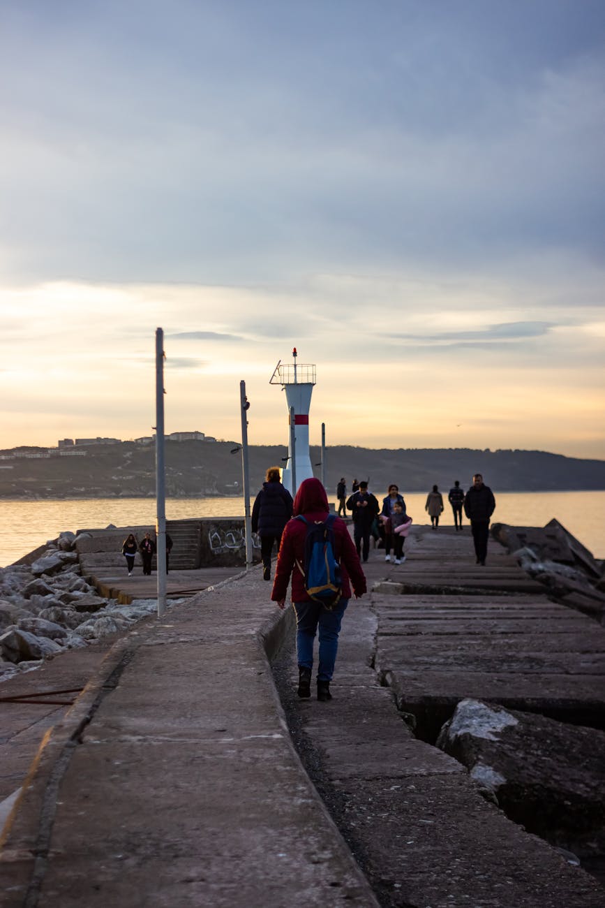 People walking on a jetty during sunset in Istanbul, creating a serene coastal landscape.