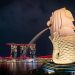 Night view of the iconic Merlion statue with Marina Bay Sands illuminated in Singapore.