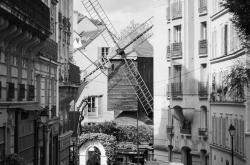 Black and white photo of a Montmartre street with a windmill, Paris, France.