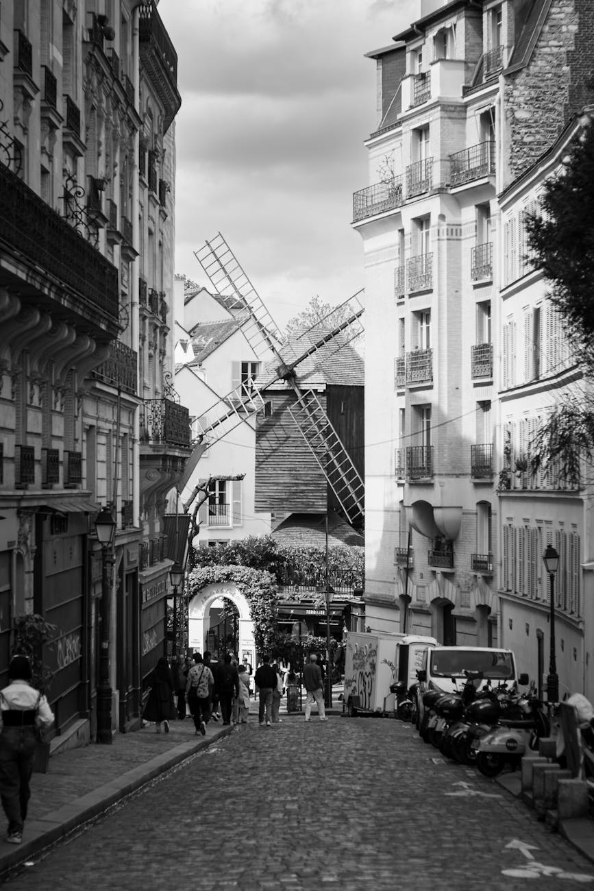 Black and white photo of a Montmartre street with a windmill, Paris, France.