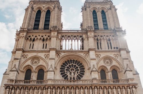 Stunning low angle view of Notre-Dame's Gothic architecture under a blue sky.