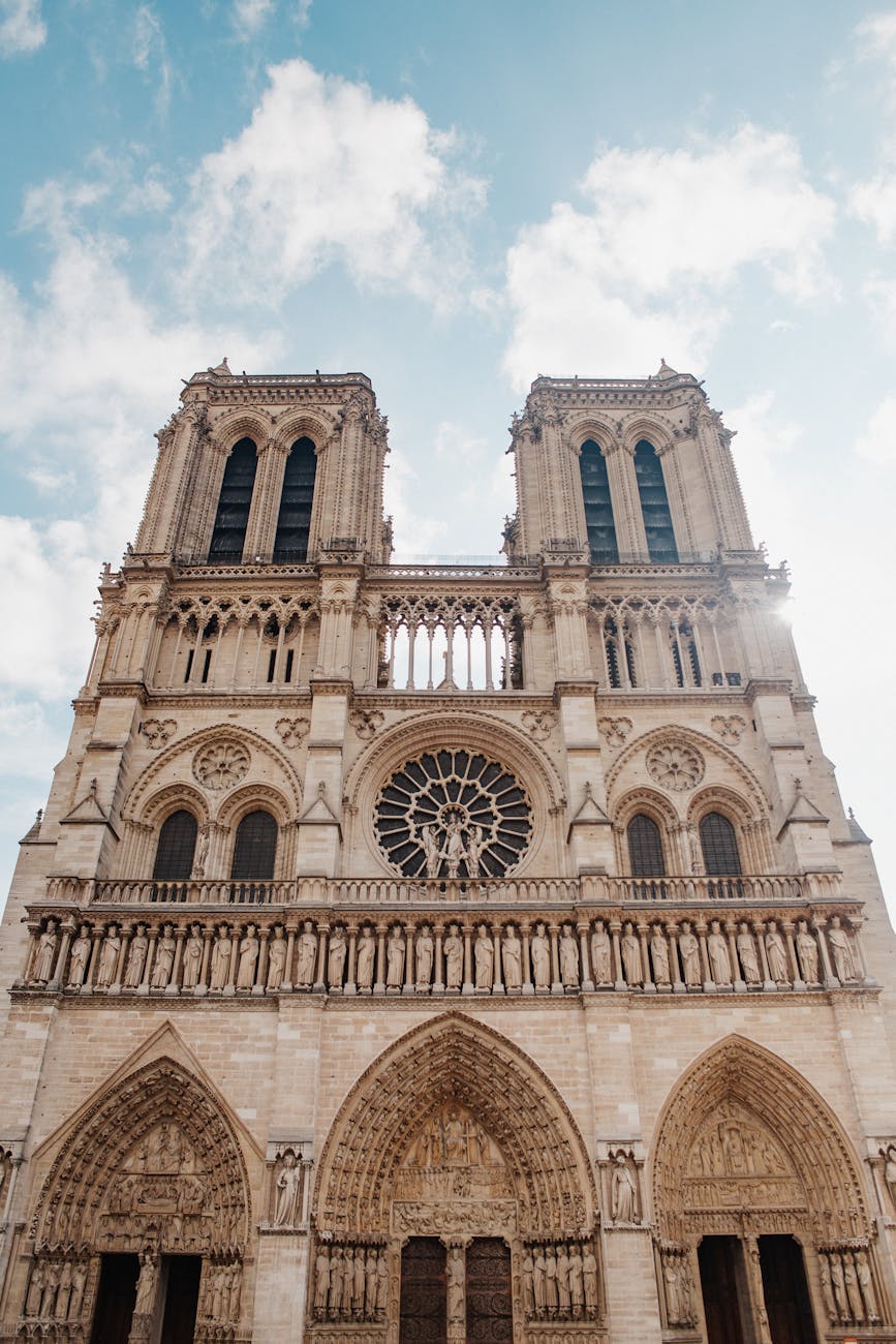 Stunning low angle view of Notre-Dame's Gothic architecture under a blue sky.