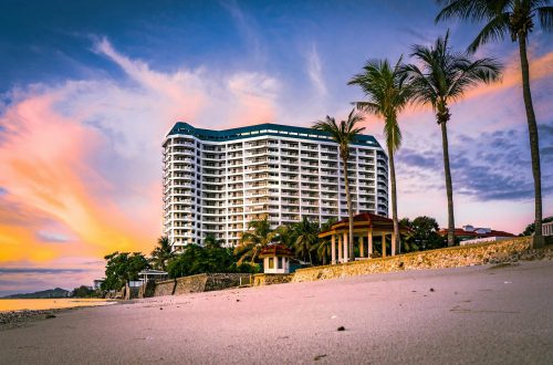 Stunning view of a beachfront resort with palm trees silhouetted against a vibrant sunset.