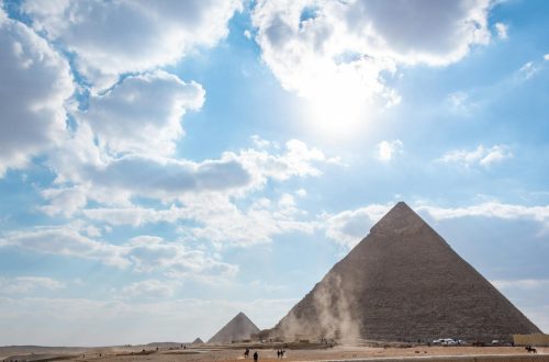 A stunning view of the Giza pyramids beneath a bright, cloud-dotted sky, perfect for travel enthusiasts.