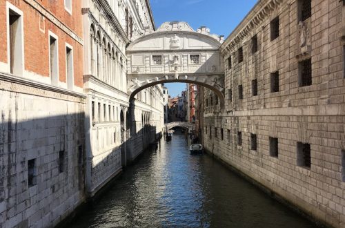 Iconic Bridge of Sighs over a Venetian canal under a clear blue sky.
