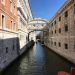 Iconic Bridge of Sighs over a Venetian canal under a clear blue sky.