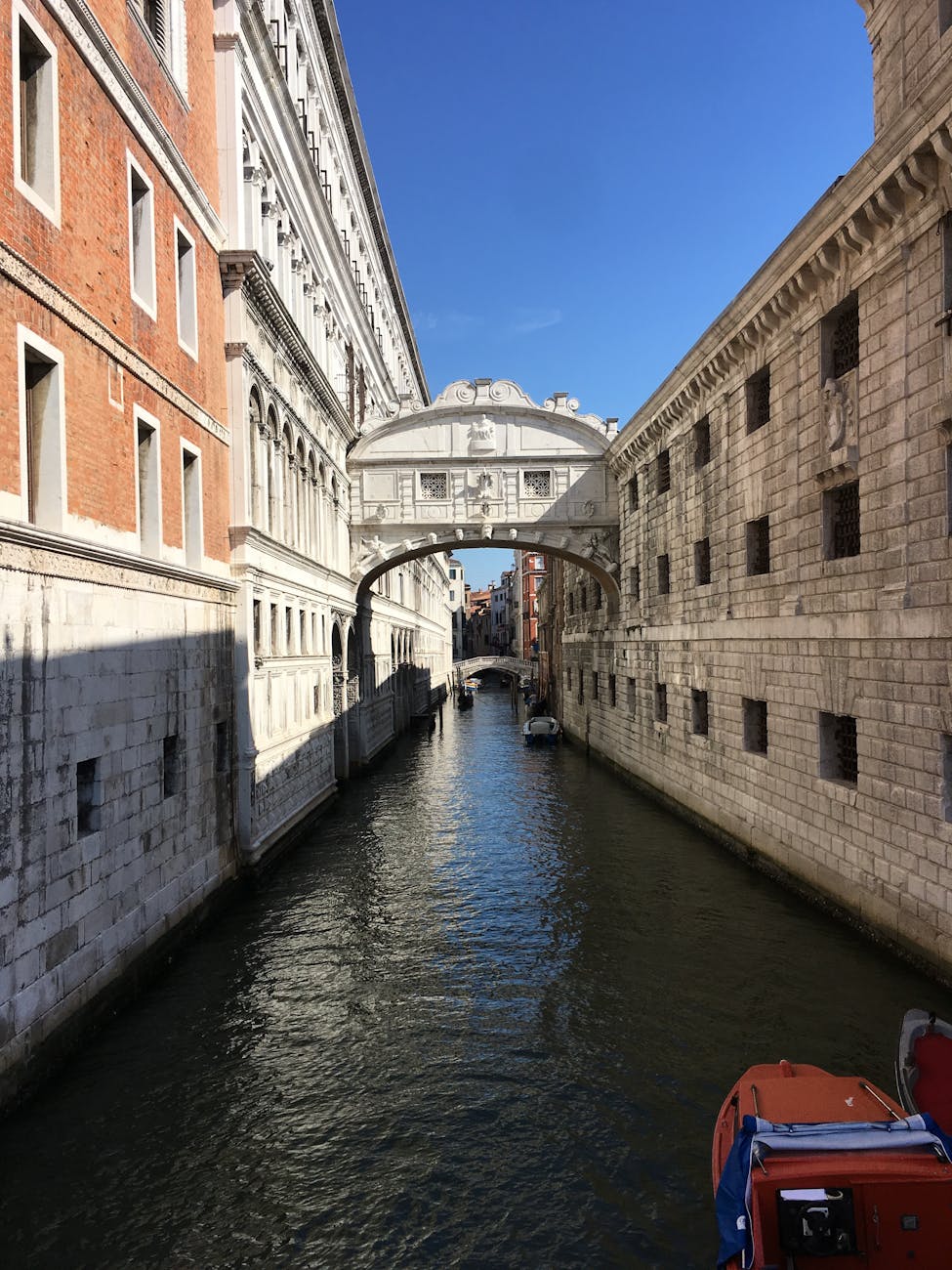 Iconic Bridge of Sighs over a Venetian canal under a clear blue sky.
