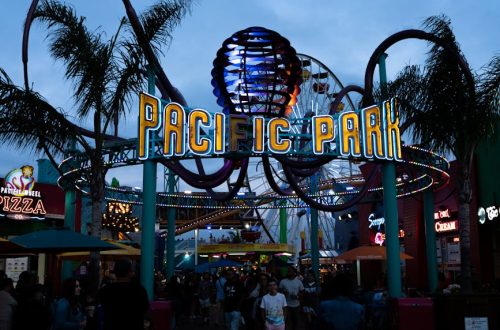 People gather at Pacific Park entrance on Santa Monica Pier at dusk, California.