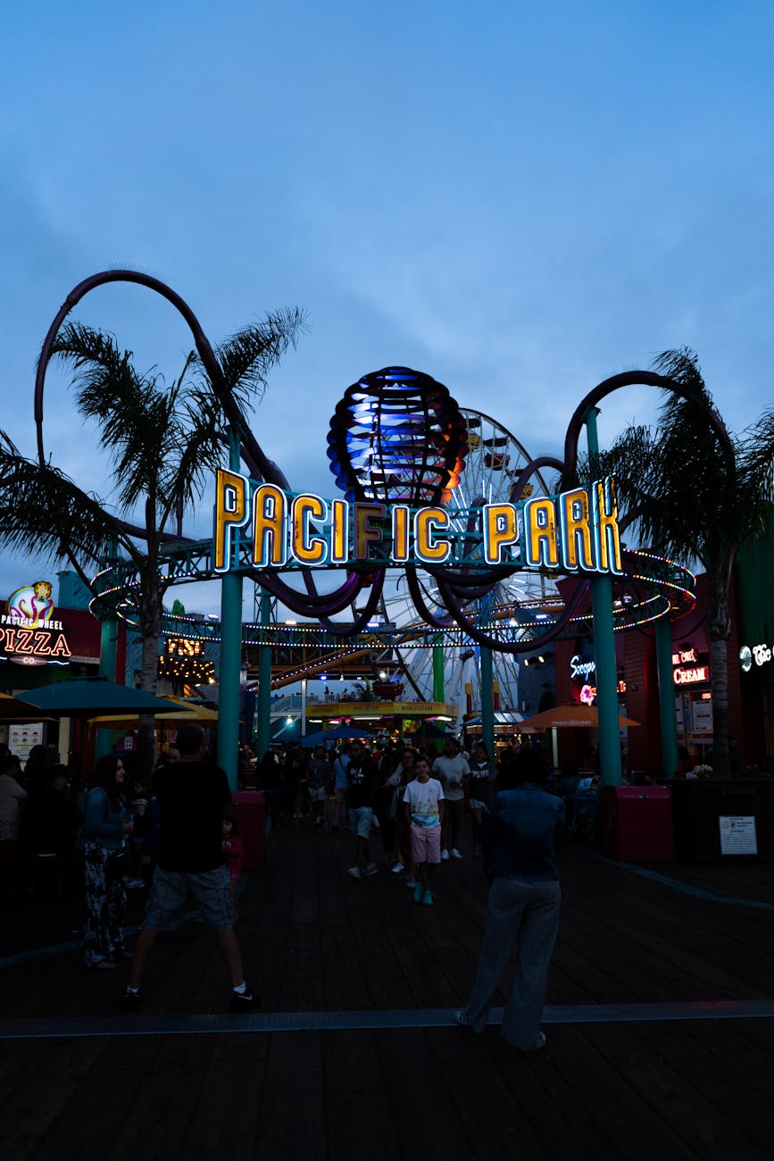 People gather at Pacific Park entrance on Santa Monica Pier at dusk, California.