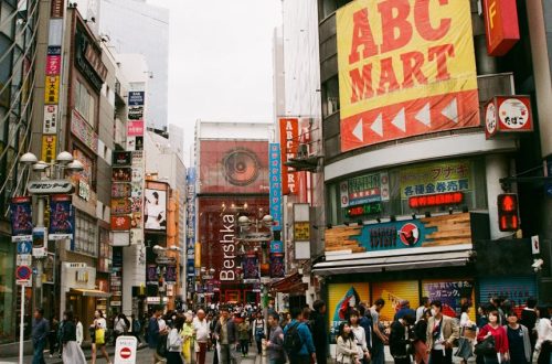 Vibrant crosswalk scene in Shibuya, Tokyo with pedestrians and colorful billboards.