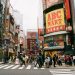 Vibrant crosswalk scene in Shibuya, Tokyo with pedestrians and colorful billboards.