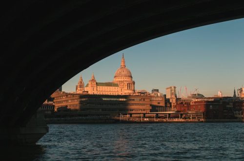 A breathtaking shot of St. Paul's Cathedral seen through a bridge over the Thames River at sunset.