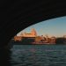 A breathtaking shot of St. Paul's Cathedral seen through a bridge over the Thames River at sunset.