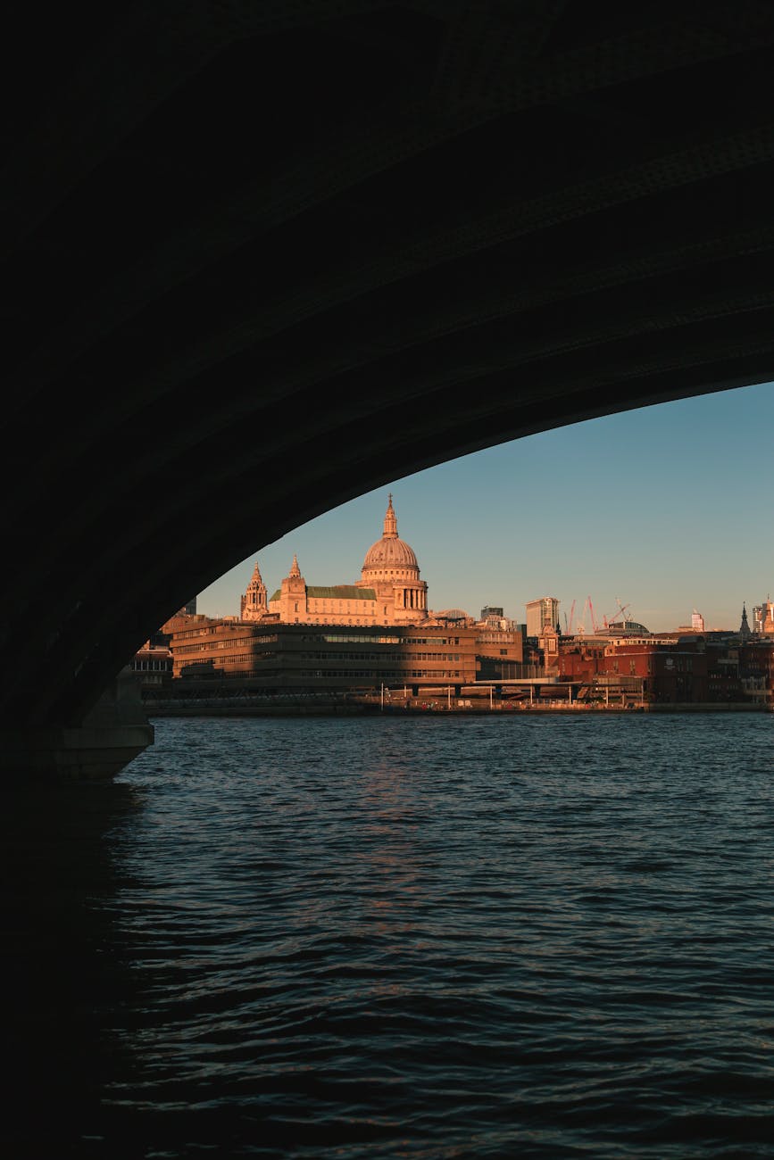 A breathtaking shot of St. Paul's Cathedral seen through a bridge over the Thames River at sunset.