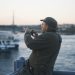 Older man using smartphone to capture scenic view of Istanbul waterfront during sunset.