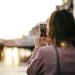 A woman takes a photo of London's skyline with her smartphone during a sunset stroll.